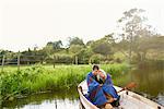 Young couple wrapped and huddled in blanket in river rowing boat