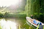 Young woman with boyfriend touching water from river  rowing boat