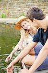 Young couple touching water from rowing boat on rural river