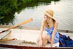 Portrait of young woman with long blond hair in rowing boat on river