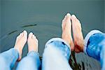 Overhead view of bare feet and legs of young couple on river footbridge