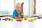 Male toddler playing with building bricks on living room floor