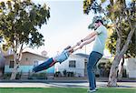 Father swinging son around, outdoors