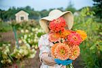 Senior woman holding flowers in front of face on farm