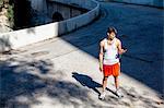 Jogger selecting music on smartphone, Arroyo Seco Park, Pasadena, California, USA