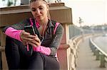 Jogger using cellular phone on bridge, Arroyo Seco Park, Pasadena, California, USA