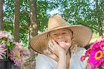 Portrait of senior female farmer wearing sun hat with cut flowers