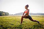 Young female runner stretching in rural park