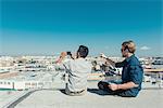 Businessmen taking photograph with smartphone on roof terrace, Los Angeles, California, USA
