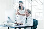 Business people working on computer by office window