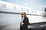 Portrait of female businesswoman and private jet at airport