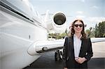 Portrait of mid adult female businesswoman and private jet at airport