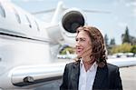 Mid adult female businesswoman and private jet at airport