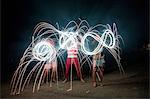 Four adult friends making sparkler patterns in darkness on Independence Day, USA