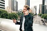 Businessman talking on smartphone from footbridge, Los Angeles, USA