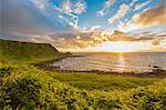 Sun setting on horizon over ocean, Giants Causeway, Bushmills, County Antrim, Ireland, UK