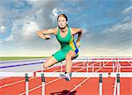Runner jumping over hurdle on track