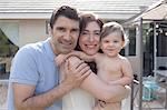 Family with baby boy hugging and smiling looking at camera smiling