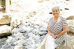 Portrait of mature woman sitting on rock, outdoors