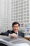 Businessman smiling, working outdoors on car