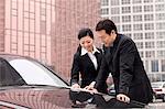 Businesspeople working outdoors on car