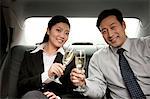 business people toasting champagne back of car