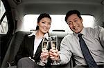 business people toasting champagne back of car
