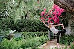 Blond woman doing yoga in a garden.