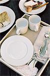 High angle view of a tray with mugs, plates and cutlery, pastries.