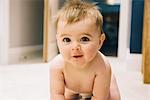 A young baby crawling on a rug.