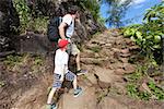 family of two hiking up together the strenuous kalalau trail along nā pali coast of the island of kauai in the state of hawaii, spending active time together at vacation