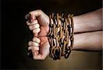Hands of a man with a rusty chain around the wrists.