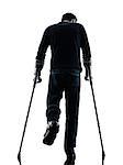 one man injured man walking with crutches rear view in silhouette studio on white background
