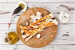 Pizza breadsticks on white wooden background with olive oil and garlic basil dip. Culinary pizza eating.