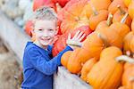 positive smiling boy choosing pumpkin at fall festival, pumpkin patch or farmers market