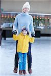 family of two ice skating at outdoor skating rink together at winter