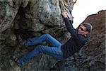 young active man rock climbing or bouldering outdoors