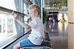 positive boy playing with toy plane at the airport waiting for departure and vacation