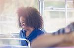 Smiling woman with afro texting with cell phone on bus