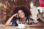 Portrait smiling woman with afro drinking coffee in cafe