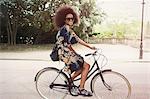 Portrait smiling woman with afro riding bicycle in urban park