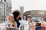 Friends with map riding double-decker bus, London, United Kingdom