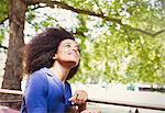 Carefree woman with afro riding double decker bus and looking up