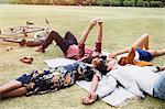 Friends relaxing and taking selfie in circle on blanket in park