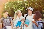 College students with books and coffee walking in park