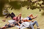 Friends taking selfie laying in circle on blanket in park