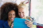 Enthusiastic friends taking selfie with digital tablet on bus