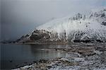 Snow covered mountains above cold lake, Norway