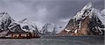 Snow covered mountain range above fishing village, Hamnoya, Lofoten Islands, Norway