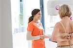 Nurse helping patient prepare for mammogram